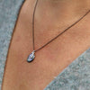 Iridescent mother of pearl set in oxidized sterling silver necklace with RTJ logo tag, hanging from black silver chain.