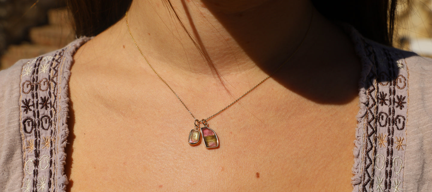 Two striped pink and green tourmaline charms set in 14K gold and hanging from a gold chain.