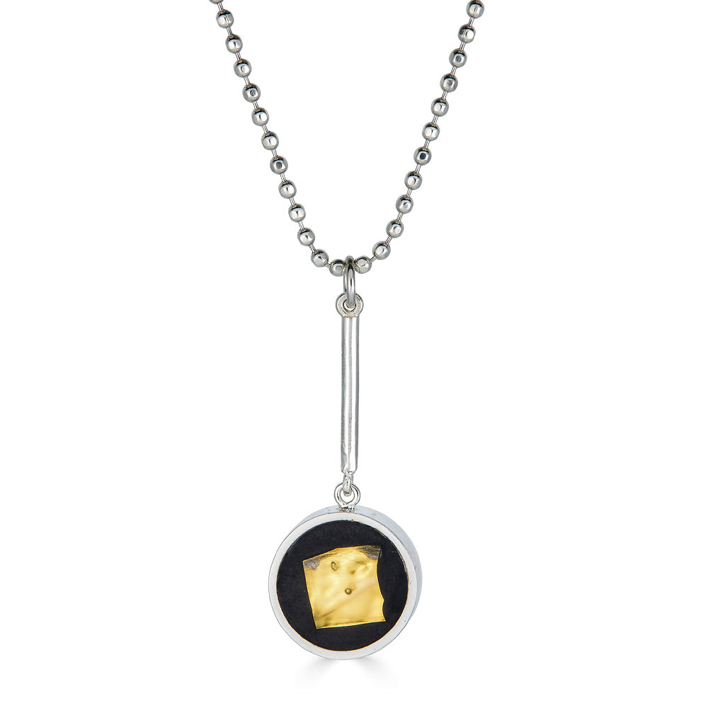 Not a Perfect Square Pendant by Ronnie Taubenfeld is a small round circular sterling silver setting with a 24k gold-fused glass smalto embedded in black resin and hangs from a silver ball chain. Handmade.