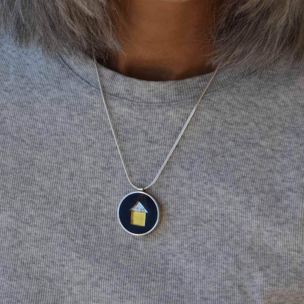 Round sterling silver pendant embedded with 24K gold and white gold-fused glass set in black resin.