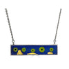 Moving Along Necklace Ronnie Taubenfeld is a handmade horizontal silver bar with green glass donuts and 24K yellow gold-fused Murano glass shapes embedded in dark resin, hanging from a silver chain.