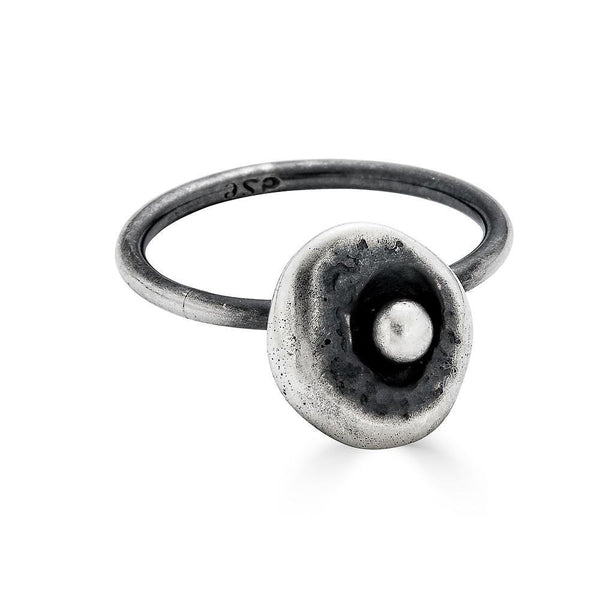 Pebble Moonscape Ring by Ronnie Taubenfeld is handmade from lightly oxidized sterling silver and has a flattened textured round shape with a bright silver ball in the center.