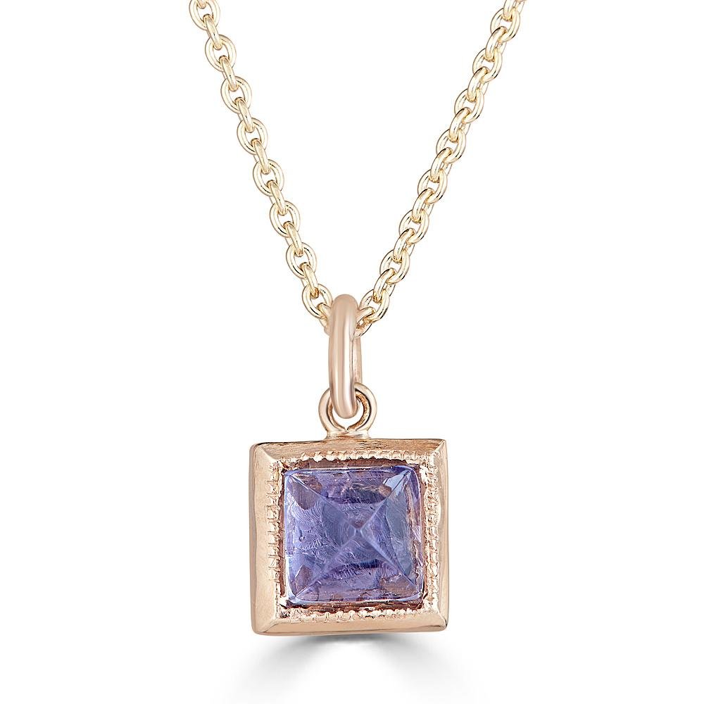 Pyramid Power Necklace by Ronnie Taubenfeld is a tiny pyramid-cut lavender Iolite gem set in a 14K gold square setting with a cutout flower on the reverse side, hanging from a gold cable chain.