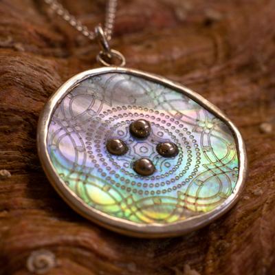 Shimmer Button Necklace by Ronnie Taubenfeld sparkling with iridescent colors shown against the outside of an abalone shell.