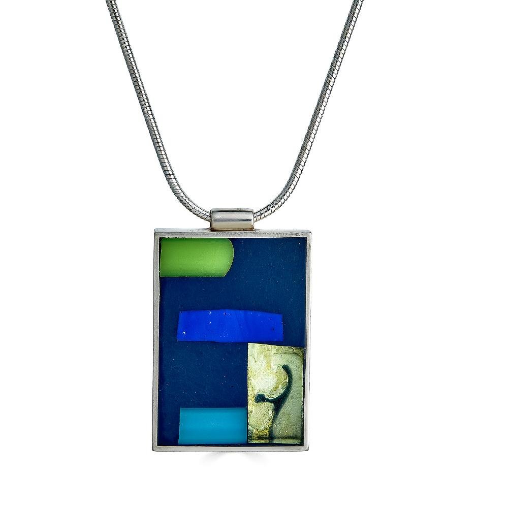 Tiny Dancer Necklace by Ronnie Taubenfeld has bright green, blue and teal stripes of glass set alongside a transparent rectangle and embedded in dark gray resin, set in a silver rectangle and hanging from a silver snake chain.