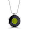 Transparent Beauty Necklace by Ronnie Taubenfeld is a transparent glass disk with a green backing embedded in black resin and set in a circular silver frame, suspended by a silver snake chain.